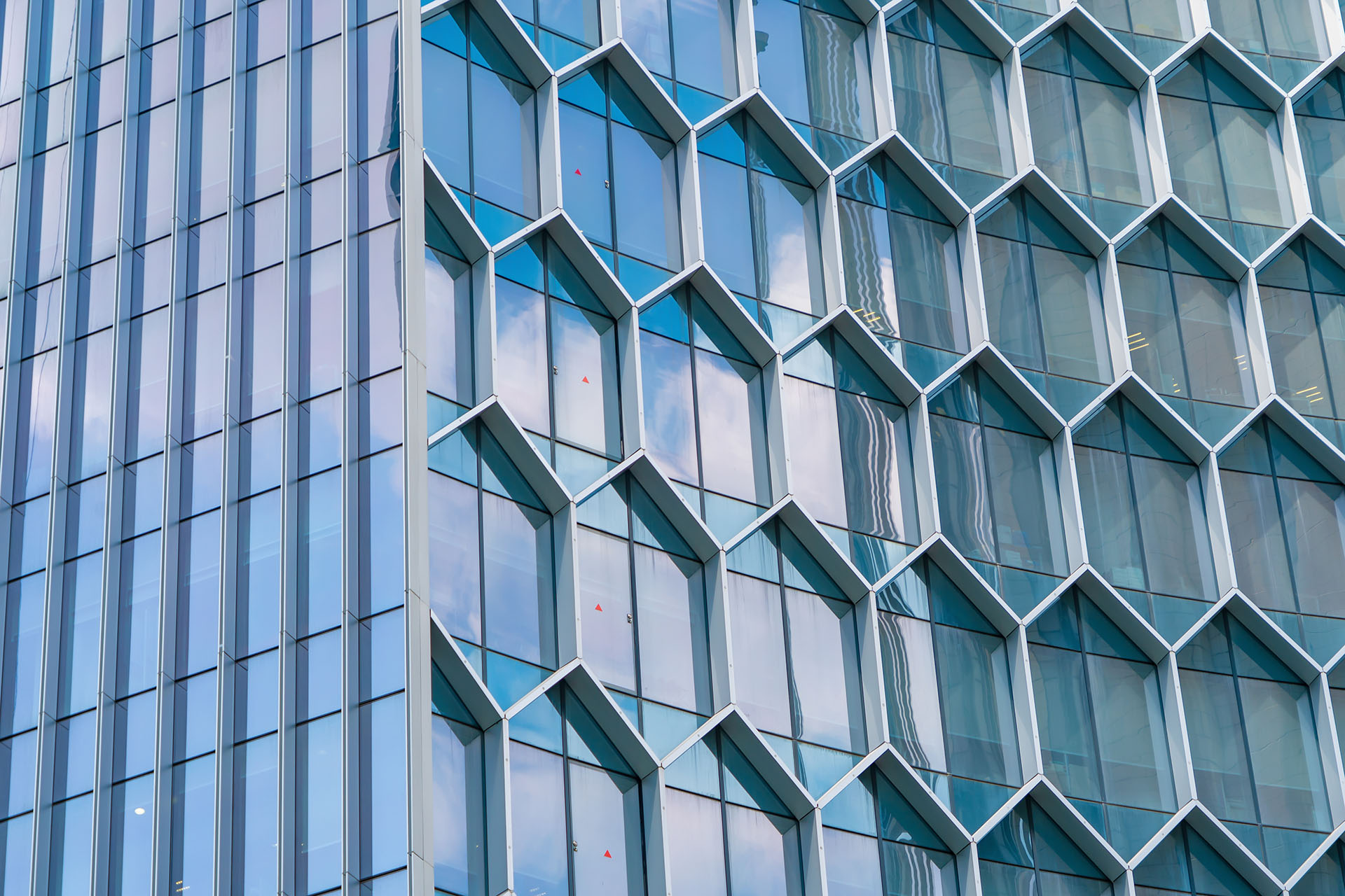 Office buildings. Structure of hexagon windows in futuristic technology network connection concept. Blue glass modern architecture facade design with reflection of sky in urban city, Downtown.